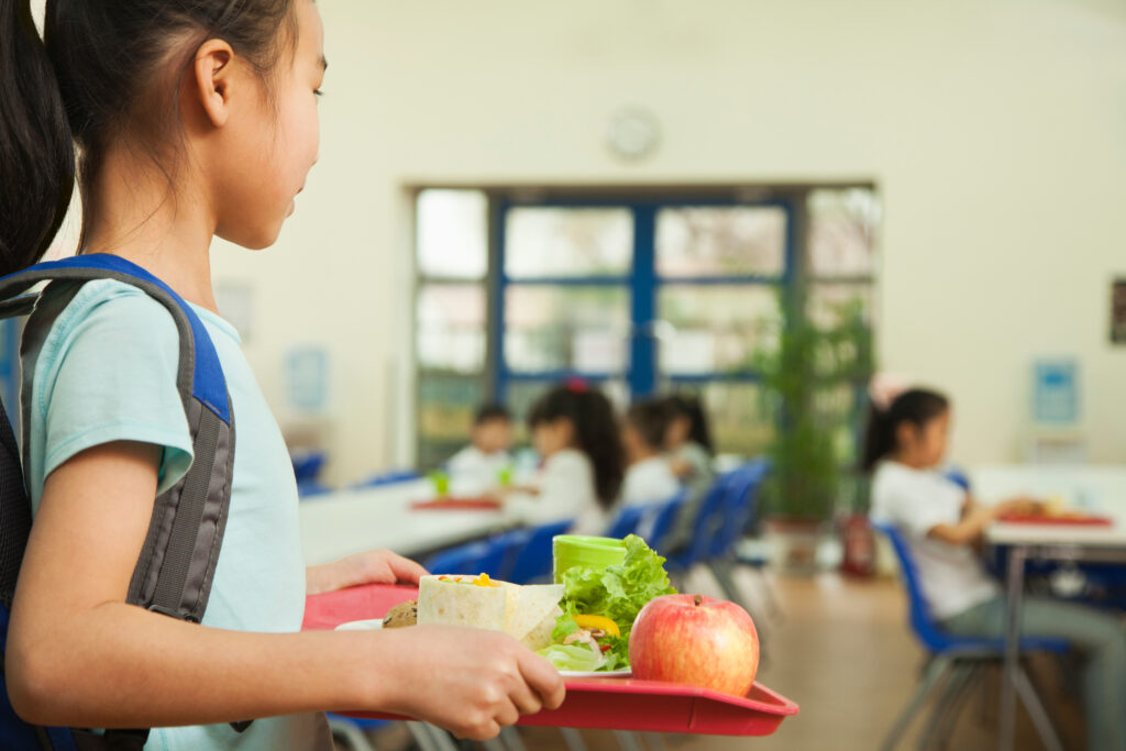 School girl holding food tray in school cafeteria - Story North Colonie's path to health and hope for every student.